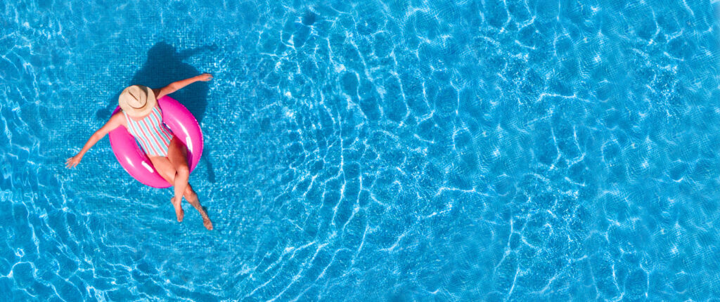 Personne se relaxant sur une bouée dans une piscine à l’eau claire.
